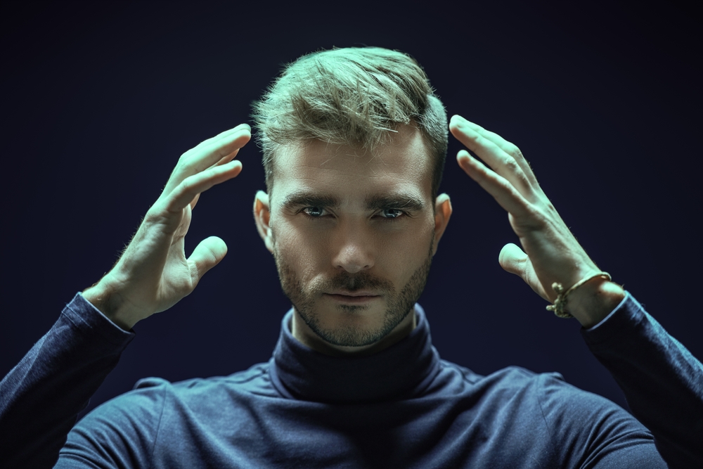 Someone with their hands next to their head communicating telepathically