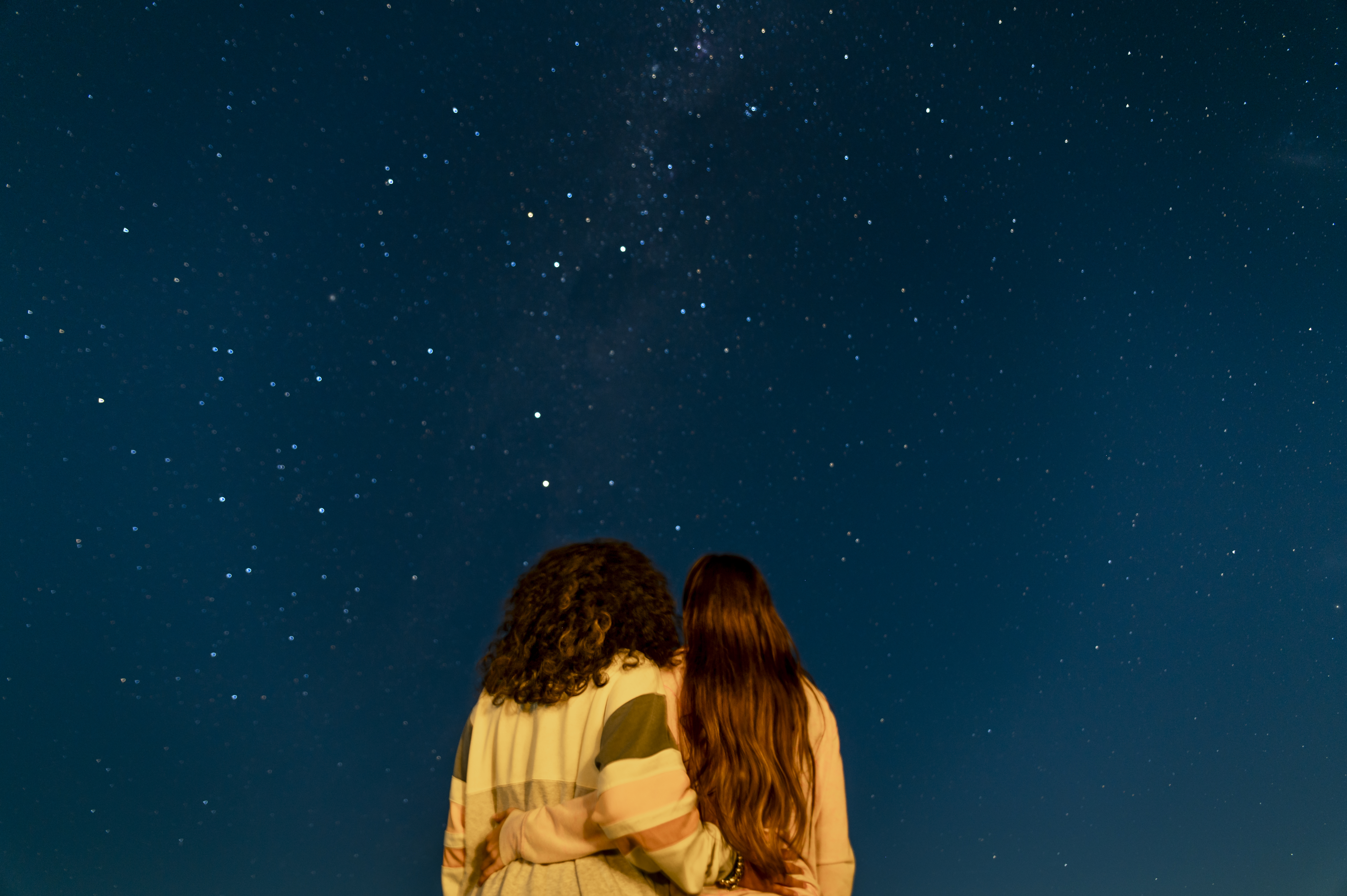 Two women wearing yellow looking up at the stars.