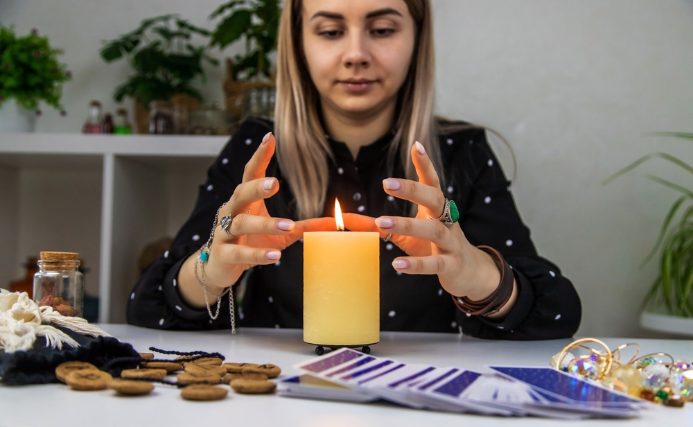 Woman practicing Clairvoyance with a candle and tarot cards