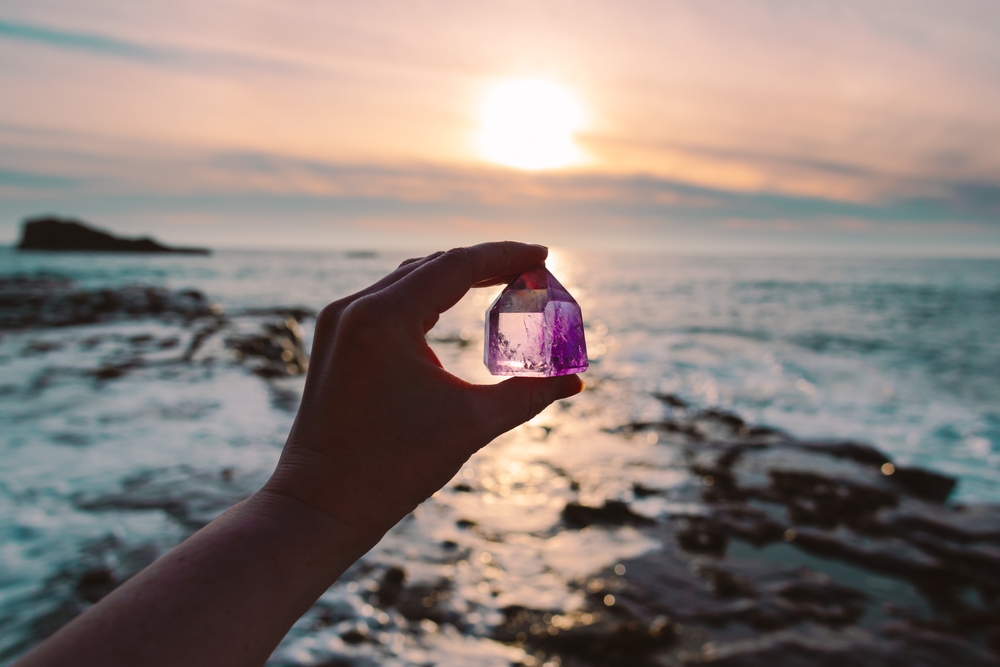 Someone holding a piece of Amethyst next to the sea
