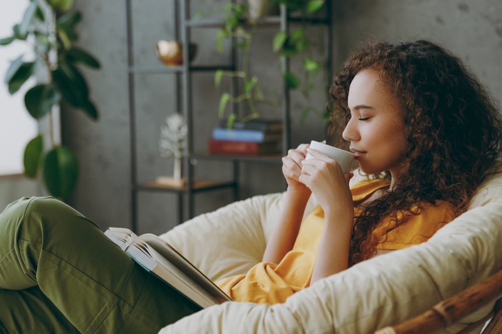 A woman relaxing reading a book and drinking tea