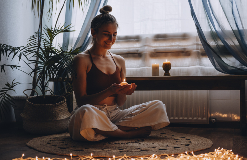 person meditating with candles and fairy lights