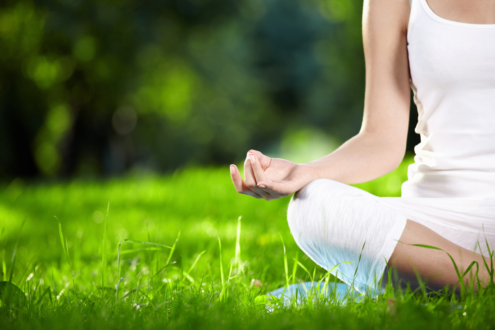 Someone meditating sitting on grass