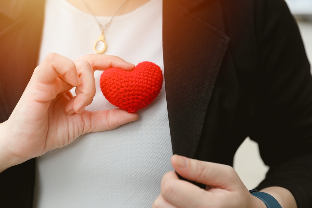 Someone holding a crochet heart over her chest