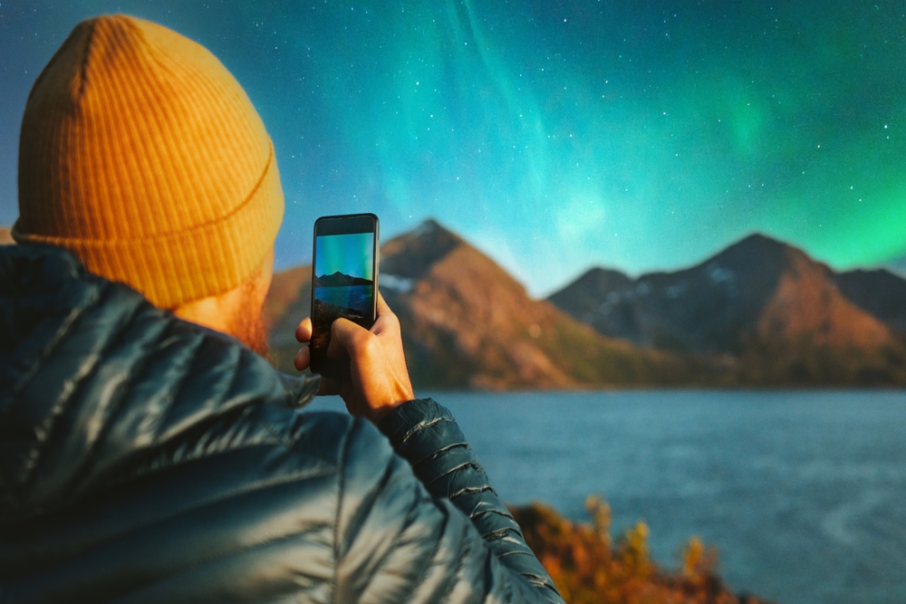 Someone taking a photo of the northern lights on a smartphone