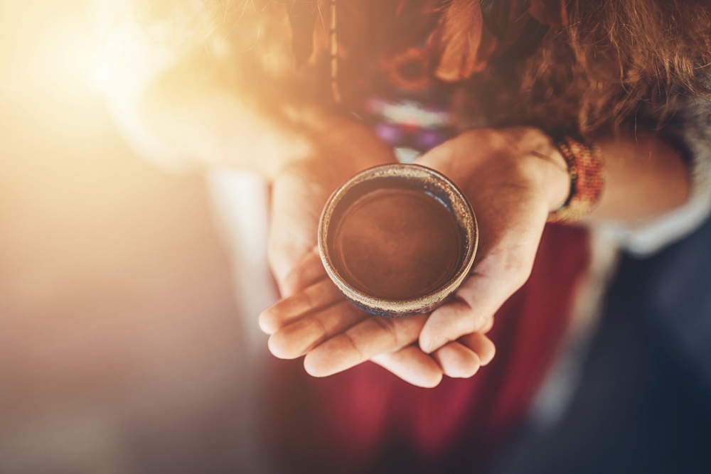 Someone holding a cup of Cacao in the palm of their hands