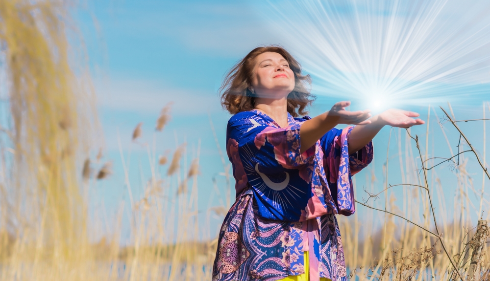 Woman outdoors meditating with visible energy force coming from her hands