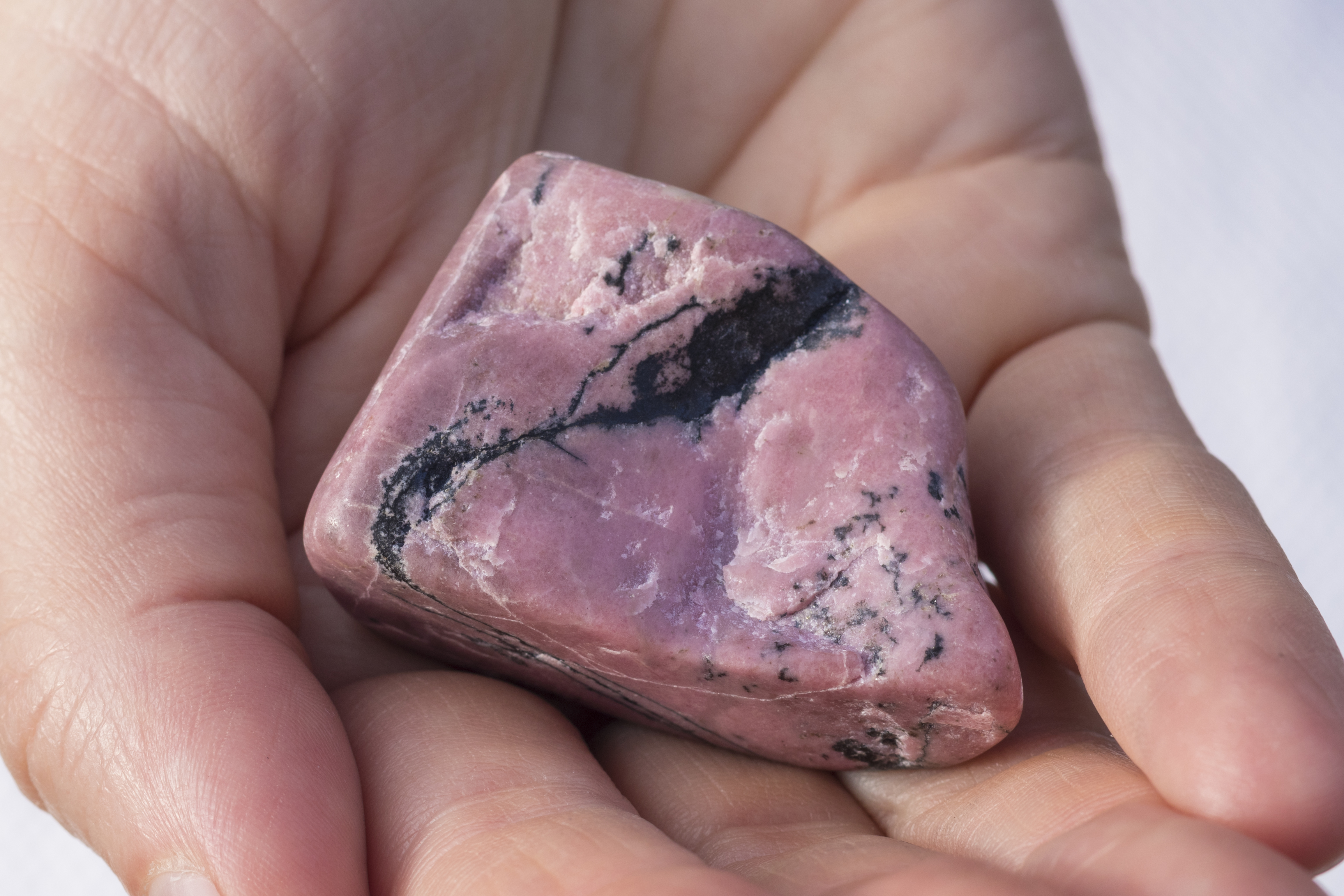 Someone holding a piece of Rhodonite in their hand